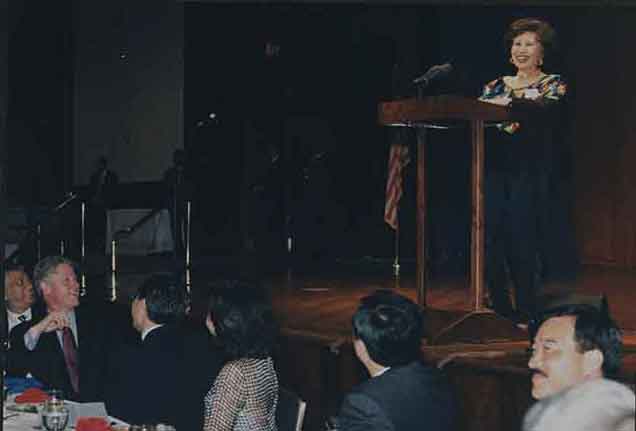 MARCH-FONG-EU-636x431-IMAGE---2---MARCH-SMILING-FROM-PODIUM-CLINTON-AT-TABLE---FRONT-WITH-FRAME---NO-GLASS---TOO-DIRTY-TO-CLEAN-300dpi-copy